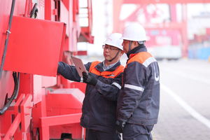 Two people waring safety helmets inspecting a harbour crane.