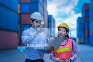 Man and woman in container yard with laptop